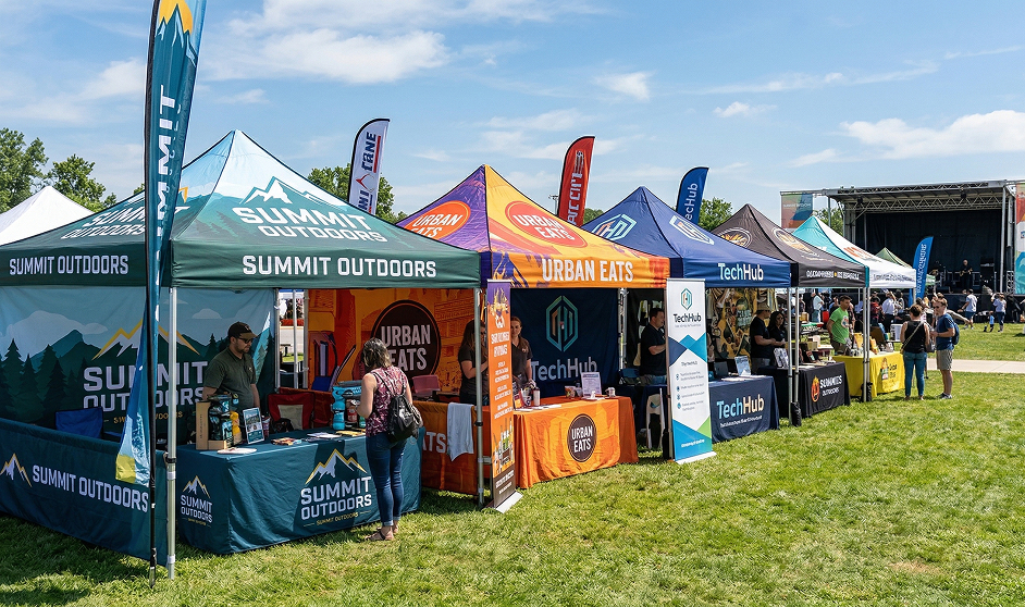 Custom branded event tent at an outdoor fair with flag banners